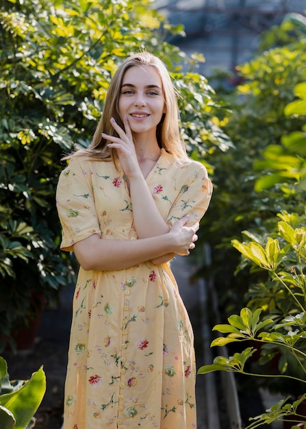 Free photo smiley woman standing surrounded by foliage