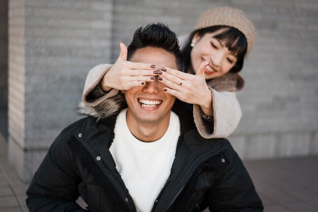 Smiley woman surprises her boyfriend outdoors