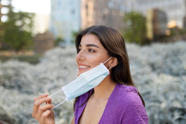 Foto gratuita donna sorridente che toglie la maschera dalla vista laterale