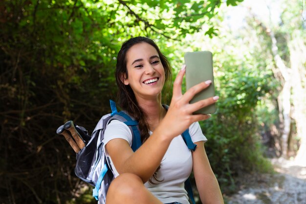 自然を探索しながら、selfieを取ってスマイリー女性