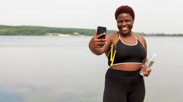 屋外でロープをジャンプしながらselfieを取ってスマイリー女性