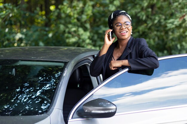 ほとんど彼女の車に乗りながら電話で話しているスマイリー女性