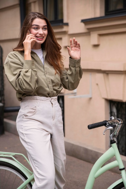 Donna sorridente che parla al telefono mentre guida la sua bicicletta