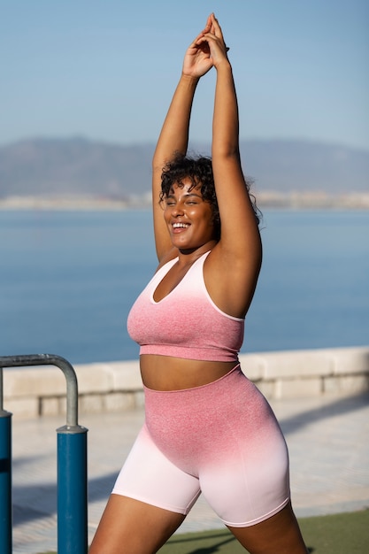 Smiley woman training outdoors side view