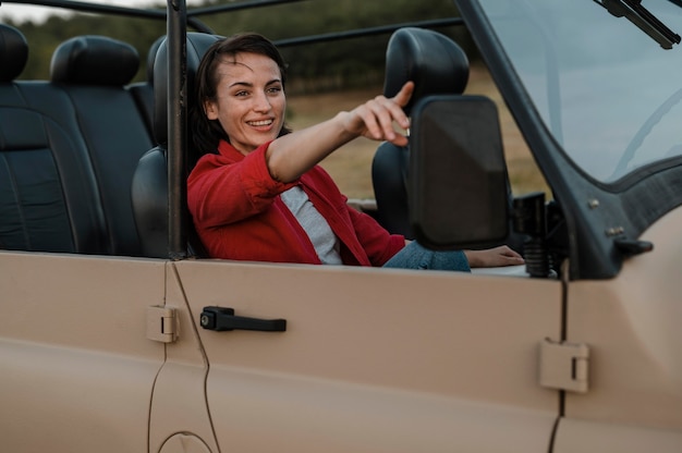 Smiley woman traveling alone by car and pointing