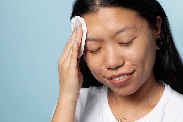 Smiley woman using cotton pad side view