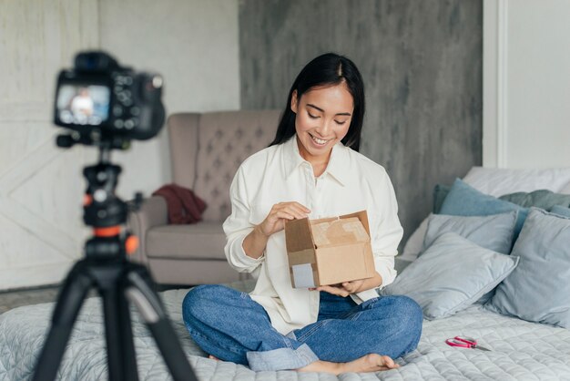 Smiley woman vlogging and looking inside a box