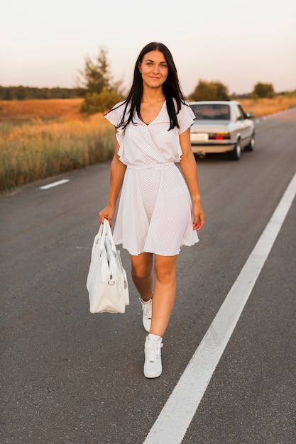 Free photo smiley woman walking away from car