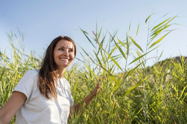 Smiley woman walking through plants with copy space