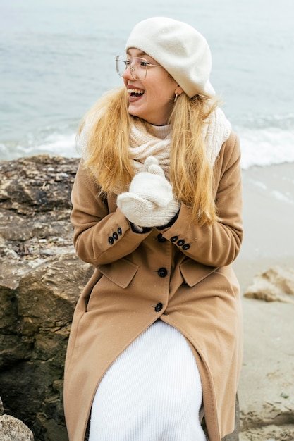 Smiley woman warming her hands at the beach during winter