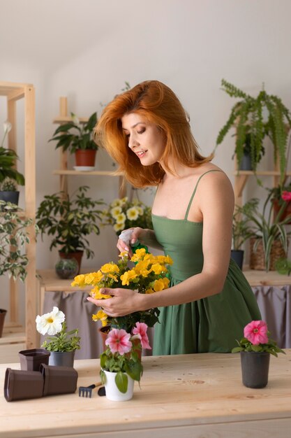 Smiley woman watering flower medium shot