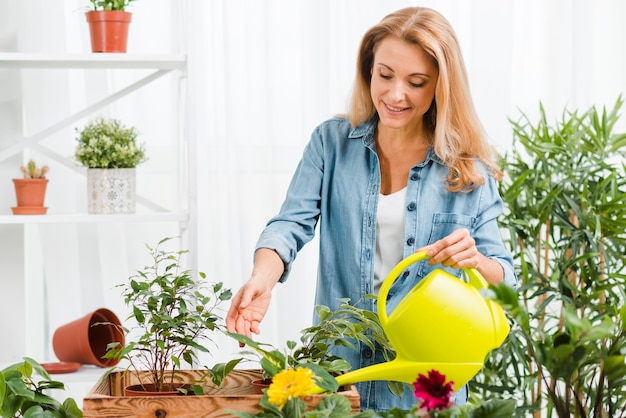 Smiley woman watering flowers