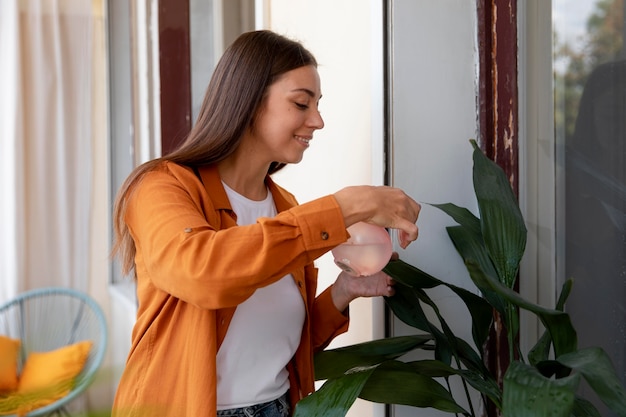 Smiley woman watering plant medium shot