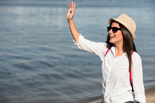 Smiley woman waving at the beach