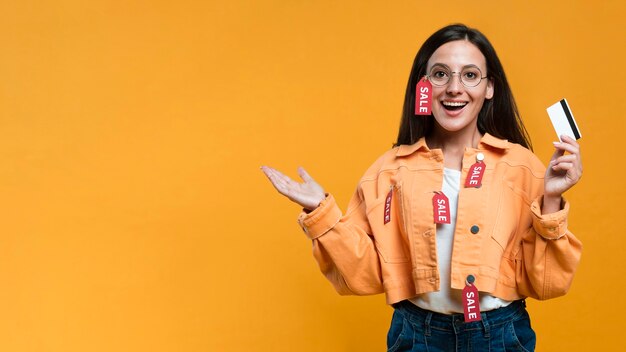 Smiley woman wearing glasses with sale tag and holding credit card