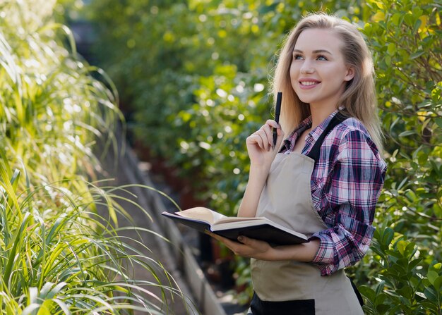 smiley woman with agenda in greenhouse