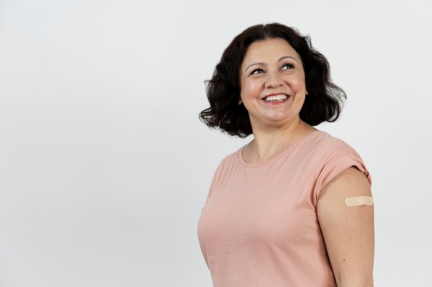 Smiley woman with bandage on arm after vaccine shot
