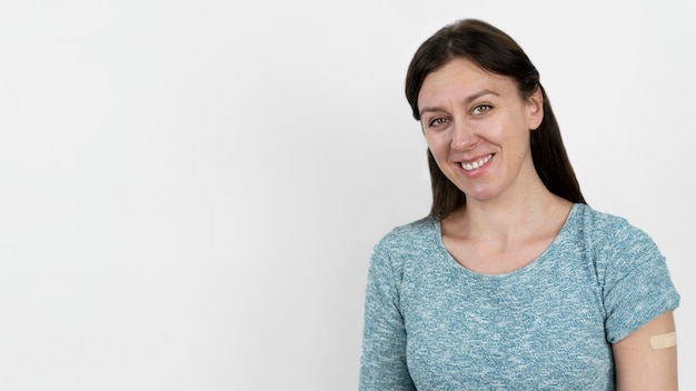 Smiley woman with bandage on arm after vaccine shot