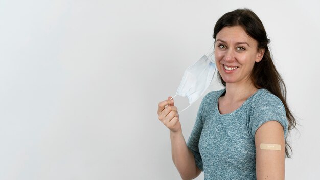 Улыбающаяся женщина с повязкой на руке после прививки