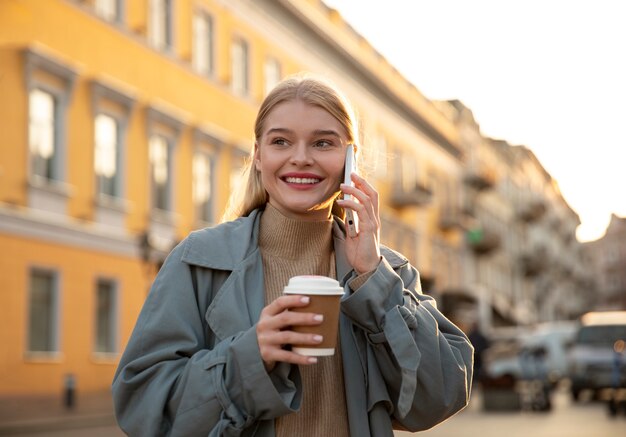 Smiley woman with coffee and phone
