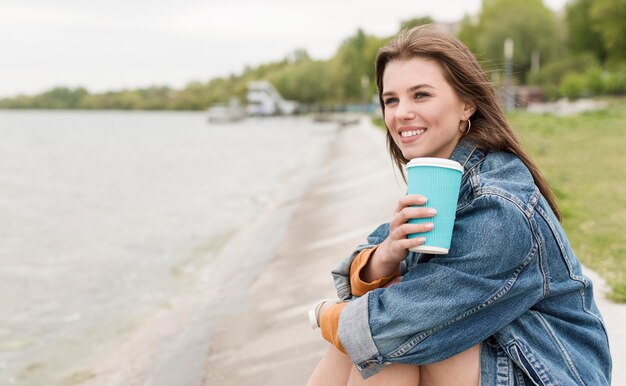 海辺でコーヒーを飲みながらスマイリー女性