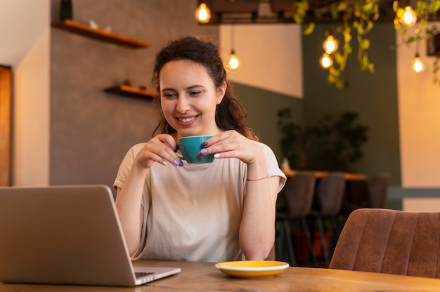 Smiley woman with cup and laptop