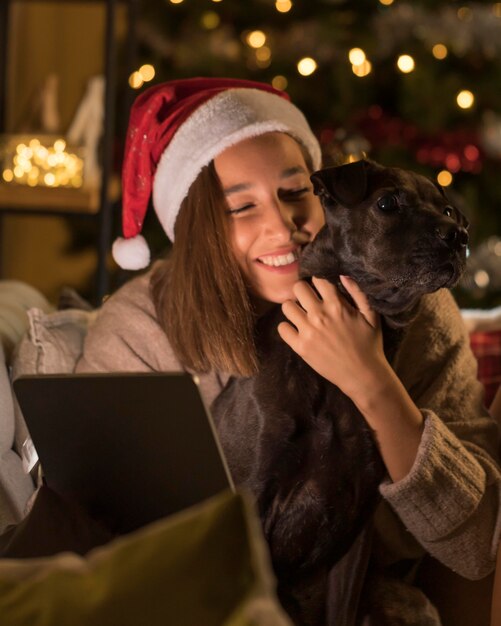 Smiley woman with dog and santa hat holding tablet