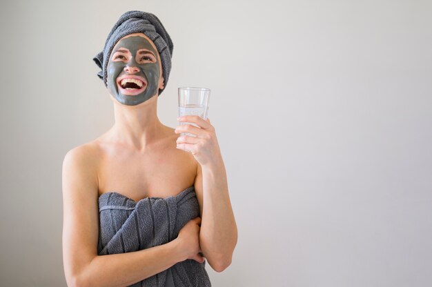 Smiley woman with face mask on holding glass of water