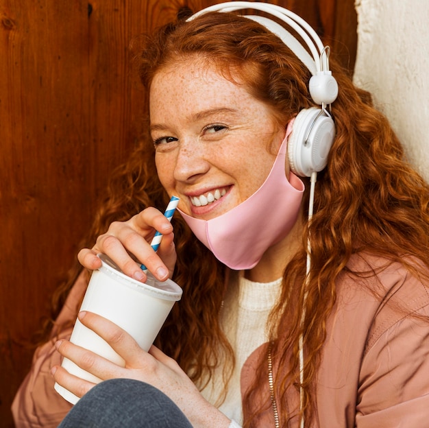 Smiley woman with face mask outdoors and headphones