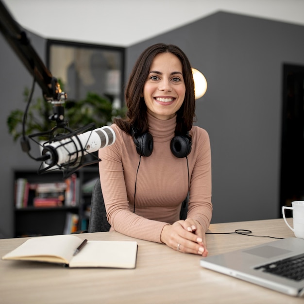 Smiley woman with microphone and notebook in a radio studio