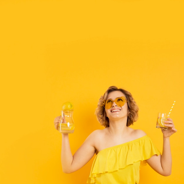 Foto gratuita donna di smiley con occhiali da sole tenendo il bicchiere di limonata