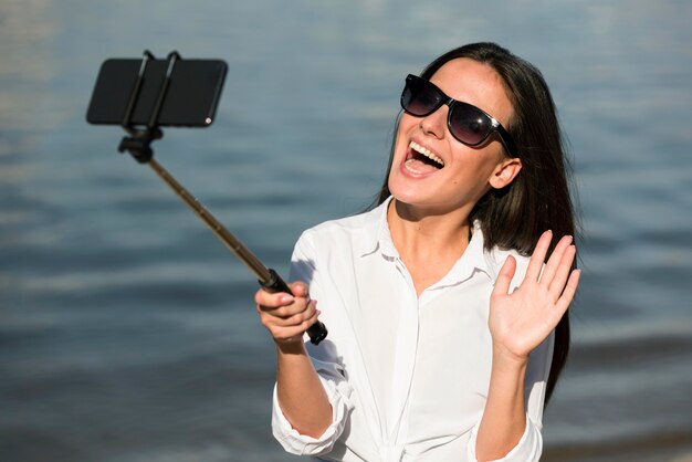 해변에서 selfie를 복용하는 선글라스와 웃는 여자
