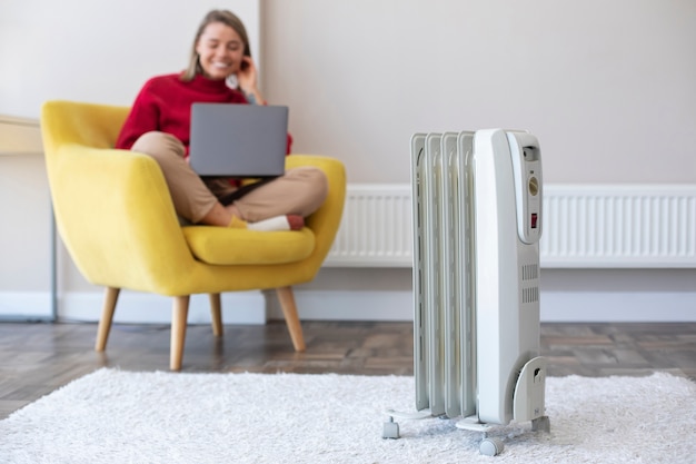 a woman working on laptop with an air heater warming the room