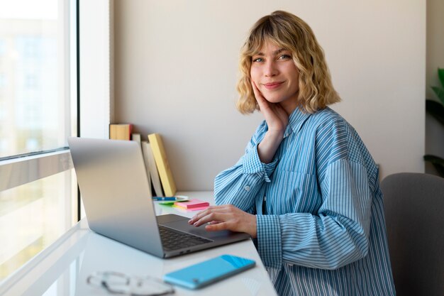 Smiley woman working on laptop side view