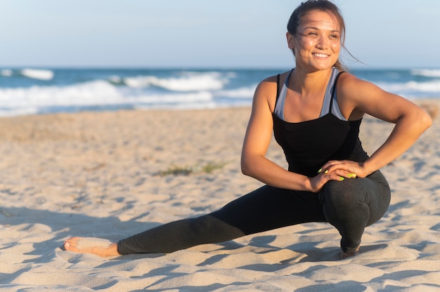 Foto gratuita donna di smiley che risolve sulla spiaggia