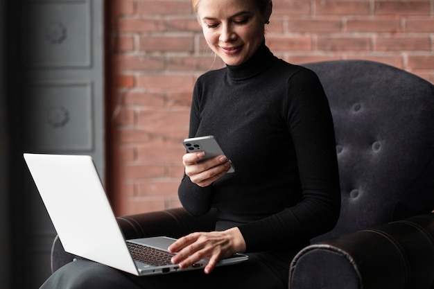 Foto gratuita donna sorridente che lavora con laptop e smartphone