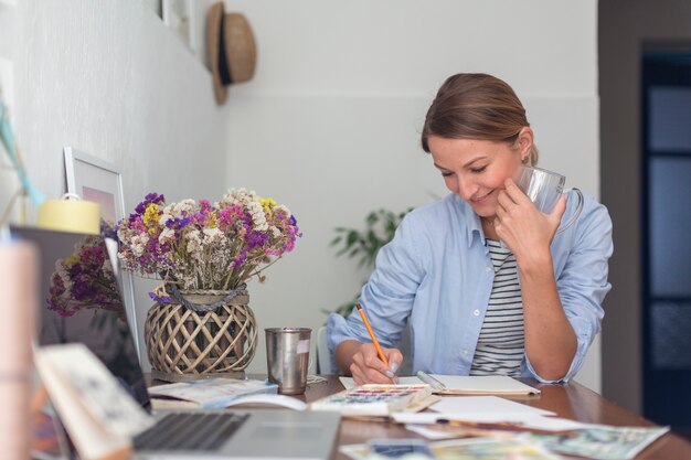 Smiley woman writing at desk in notebook