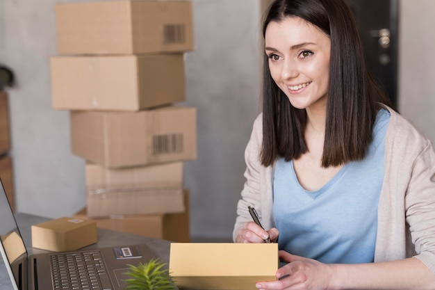 Free photo smiley woman writing something next to laptop