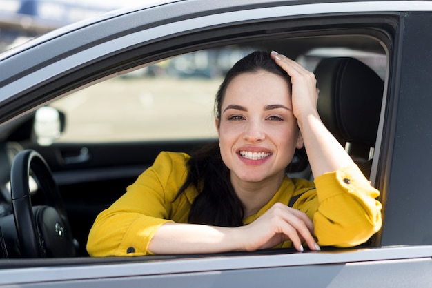 車の中で座っている黄色のシャツのスマイリー女性