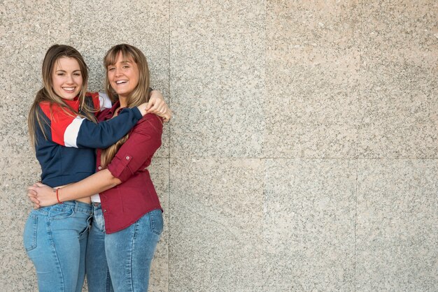 Smiley women hugging each other with copy-space