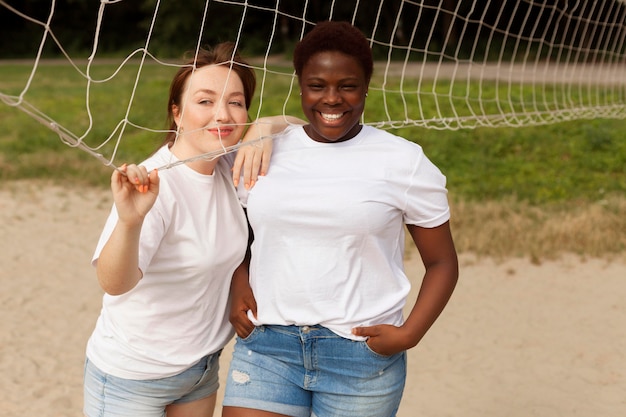 Smiley women posing together outdoors with net