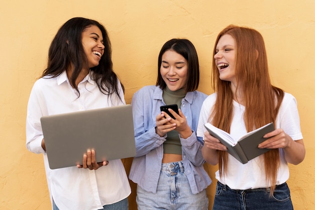 Smiley women using different objects in front of a yellow wall