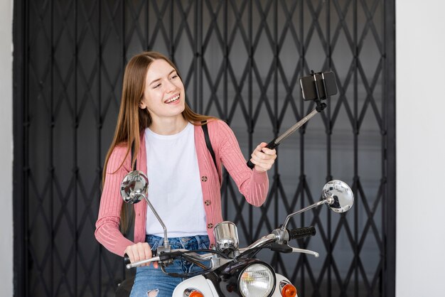 그녀의 오토바이 옆에 앉아 자신을 기록 웃는 젊은 블로거