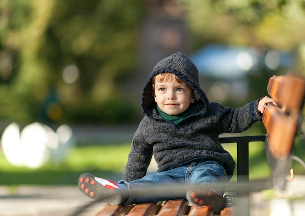 Smiley young boy holding hand on a bench