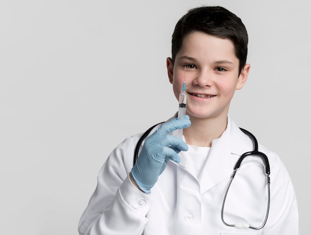 Улыбающийся мальчик держит медицинский шприц