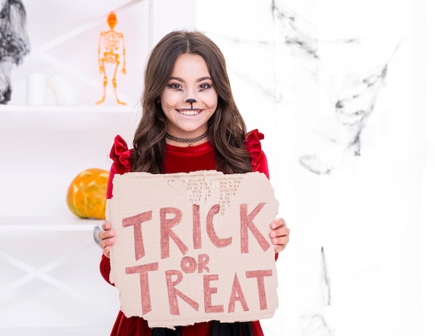 Smiley young girl holding trick or treat sign