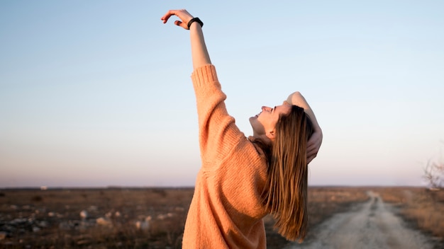 Smiley young girl on the road with her hand in the air