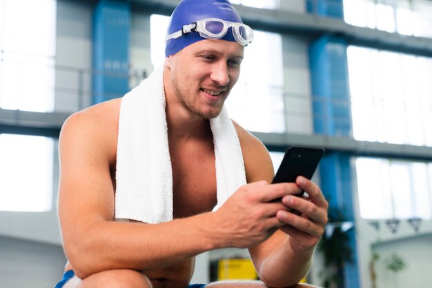 Smiley young man using phone at pool