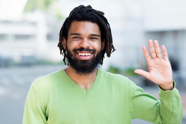 Free photo smiley young person waving in the streets