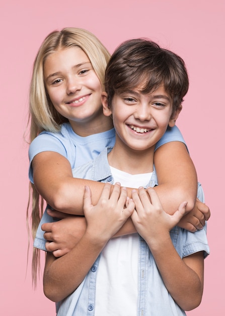 Free photo smiley young siblings hugging